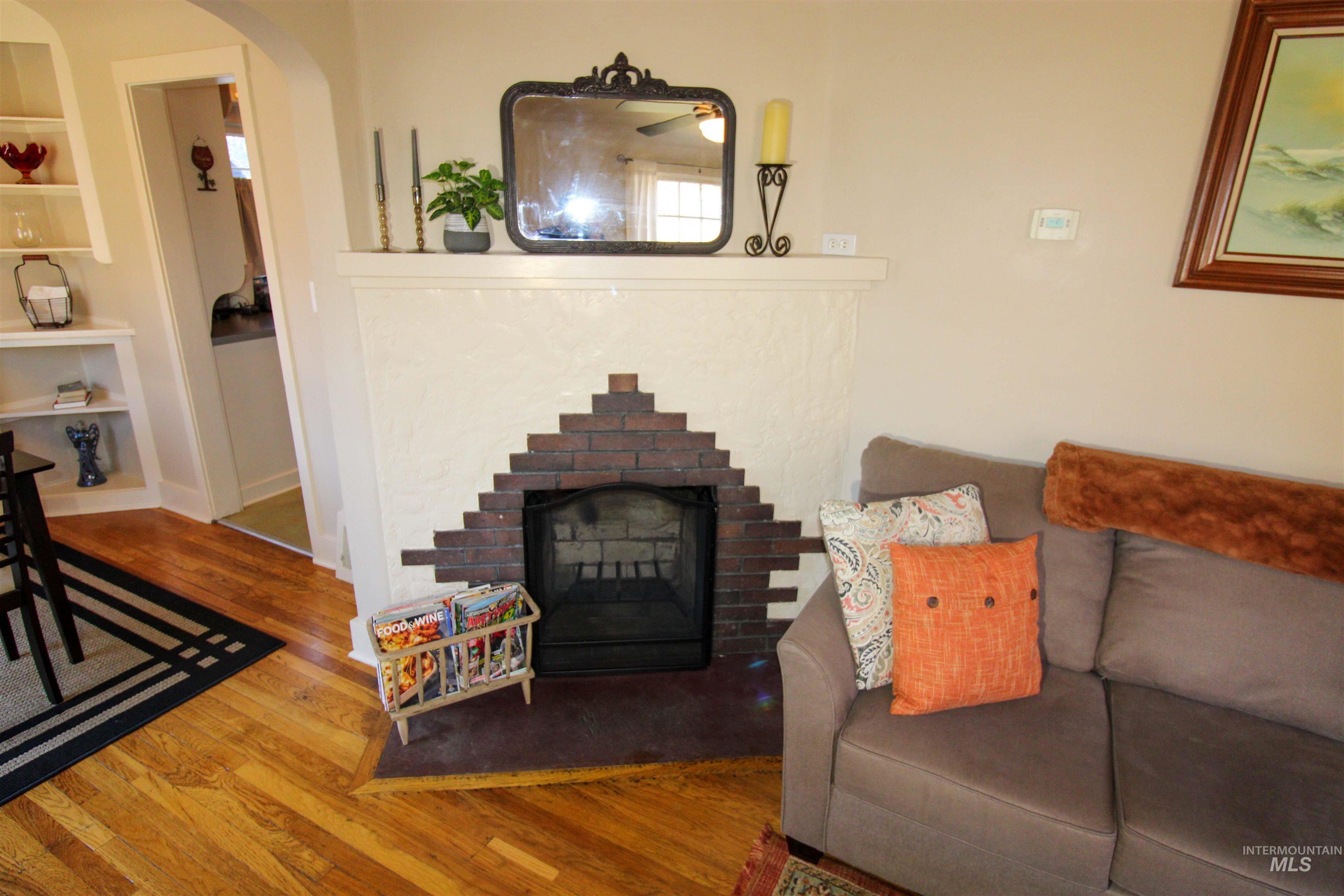 2551 West Hill Road Boise, ID 83702 - Photo 8 of 24 Living room with hardwood / wood-style floors, arched walkways, a brick fireplace, and built in shelves