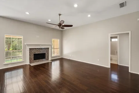 a view of an empty room with wooden floor fireplace and a window