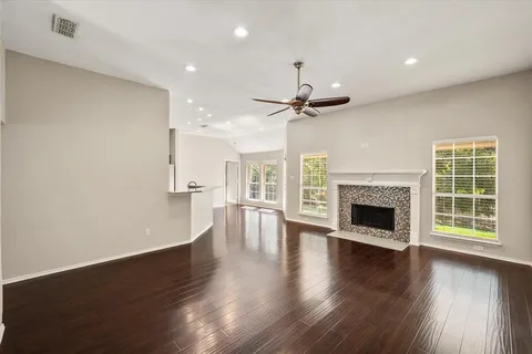 a view of an empty room with wooden floor a fireplace and a window