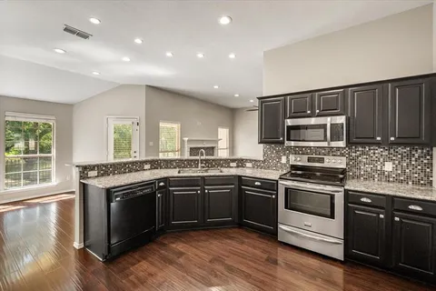 a kitchen with stainless steel appliances granite countertop a stove a sink and a microwave