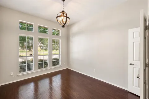 a view of an empty room with wooden floor and windows