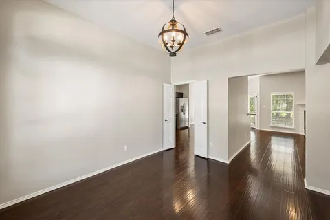 a view of an empty room with wooden floor and windows