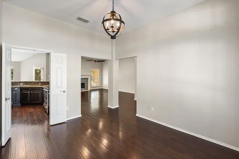 a view of a hallway with wooden floor and a kitchen