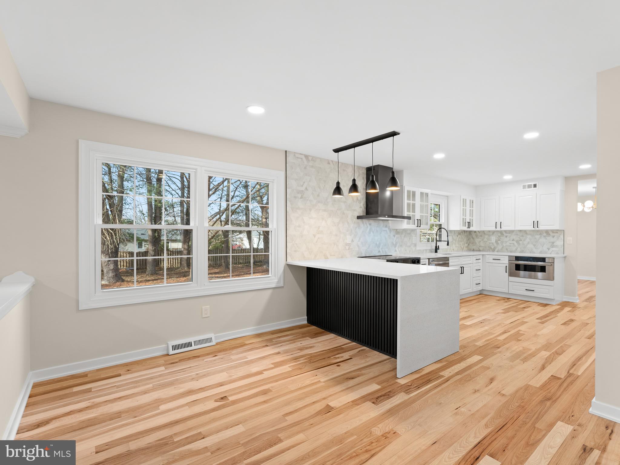 972 Roeloffs Road Yardley, PA 19067 - Photo 15 of 64 a large white kitchen with kitchen island a sink wooden floor and a large window