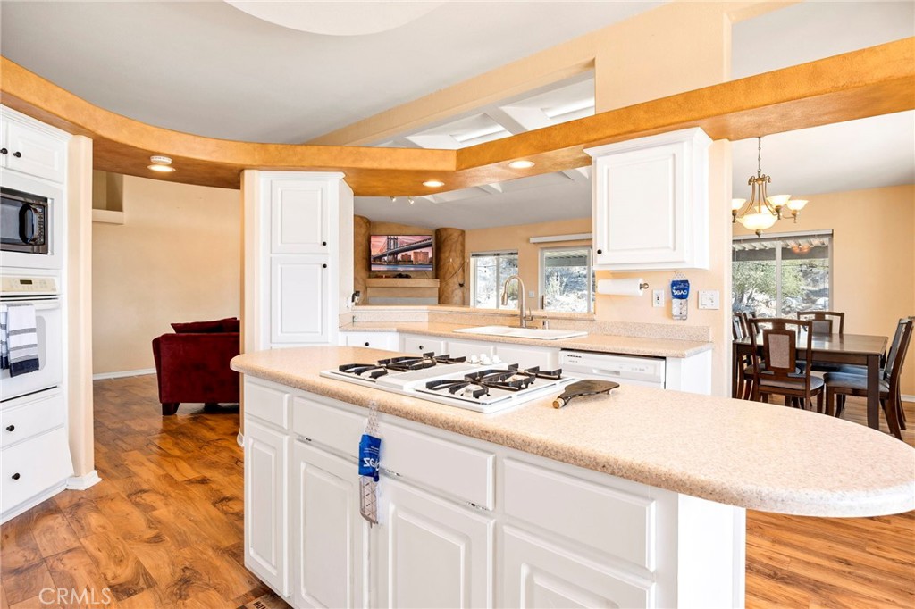 35125 Stirrup Road Temecula, CA 92592 - Photo 12 of 51 a kitchen with a stove a sink a dining table and chairs with wooden floor