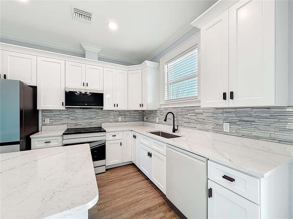 12847 Southwest 73rd Street Ocala, FL 34473 - Photo 15 of 28 a kitchen with stainless steel appliances granite countertop a sink a stove a refrigerator a microwave and cabinets
