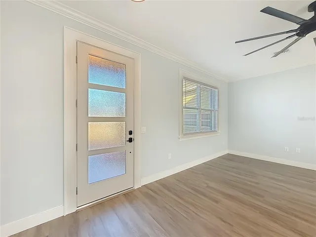 an empty room with wooden floor cabinet and windows