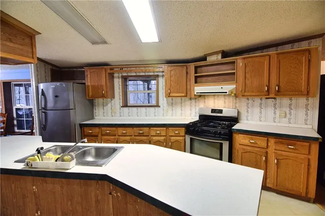 a kitchen with stainless steel appliances granite countertop a sink stove and refrigerator