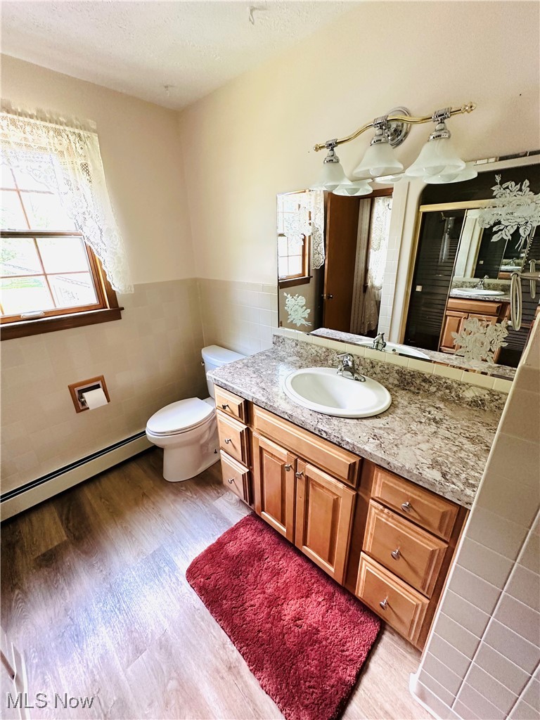 1684 Morris Street Mineral Ridge, OH 44440 - Photo 37 of 50 Bathroom with a baseboard radiator, plenty of natural light, tile walls, wainscoting, and vanity