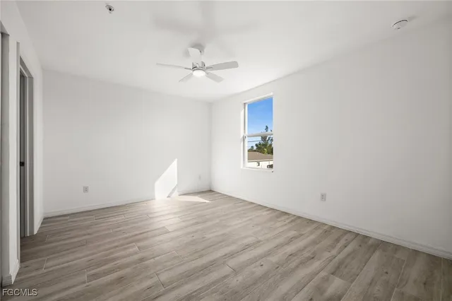 a view of an empty room with wooden floor and a ceiling fan