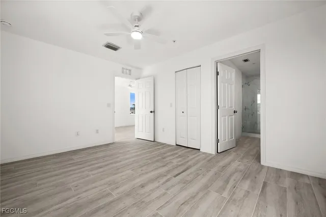 an empty room with wooden floor and a ceiling fan