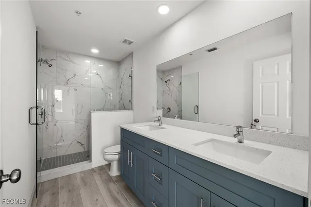 a bathroom with a sink double vanity granite toilet and shower