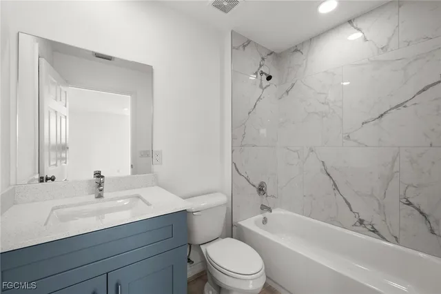 a bathroom with a bathtub shower sink vanity mirror and toilet