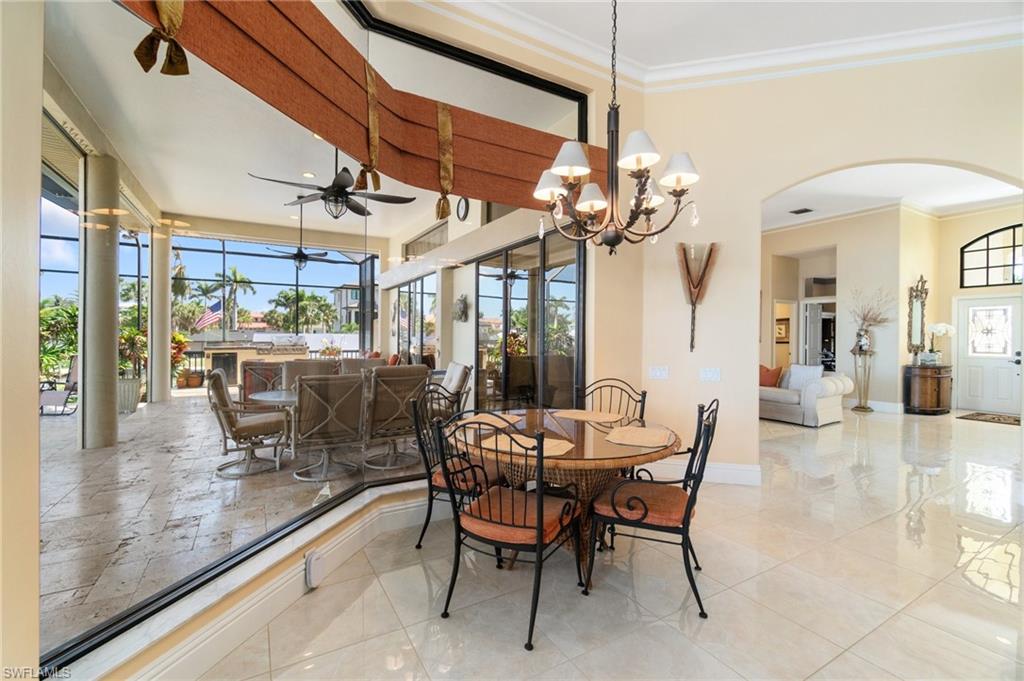 431 Palm Court Naples, FL 34108 - Photo 21 of 50 a dining room with wooden floor a chandelier a glass table and chairs