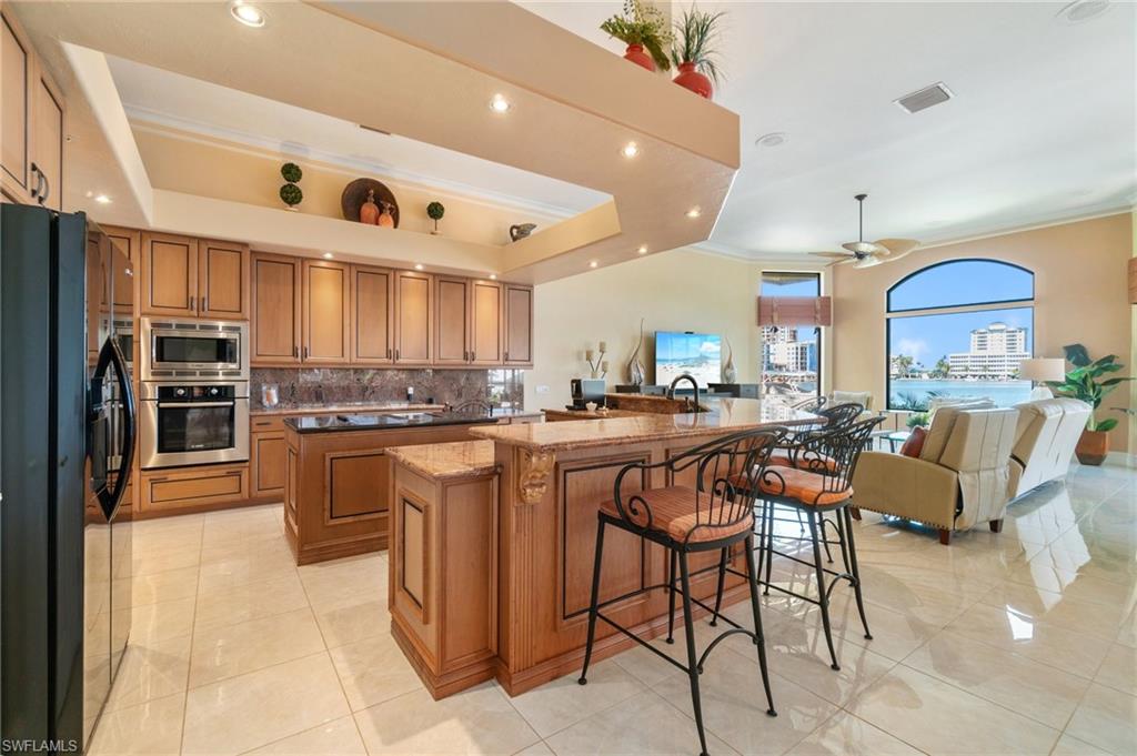 431 Palm Court Naples, FL 34108 - Photo 22 of 50 a kitchen with stainless steel appliances kitchen island granite countertop a table and chairs in it