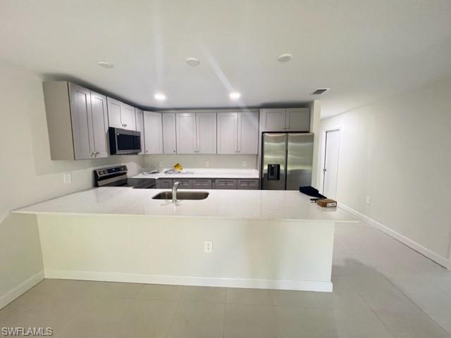4414 Douglas Lane Lehigh Acres, FL 33973 - Photo 14 of 15 Kitchen featuring stainless steel appliances, a peninsula, light stone counters, gray cabinetry, and recessed lighting