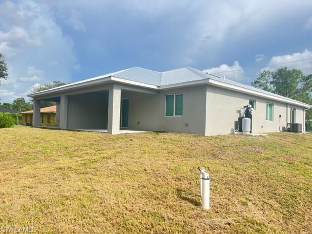 4414 Douglas Lane Lehigh Acres, FL 33973 - Photo 3 of 15 Back of property with stucco siding, a patio, and a lawn