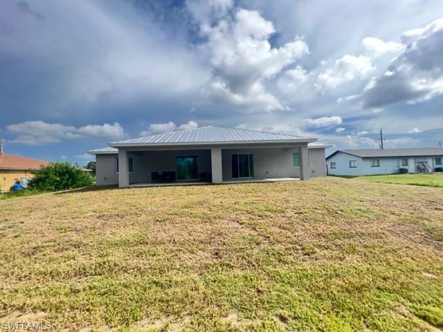 4414 Douglas Lane Lehigh Acres, FL 33973 - Photo 5 of 15 Rear view of house with a lawn, a metal roof, a patio area, and a standing seam roof