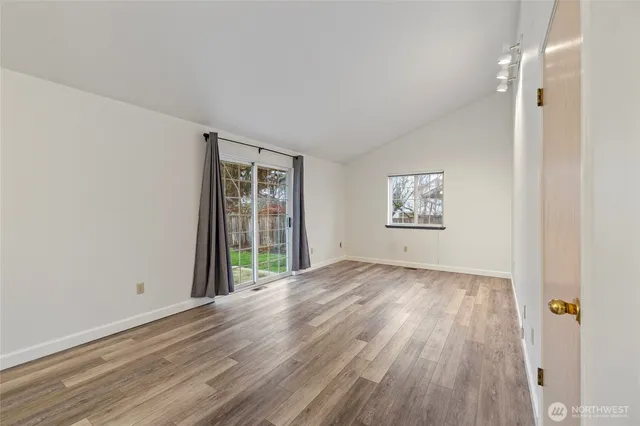 a view of an empty room with a window and wooden floor