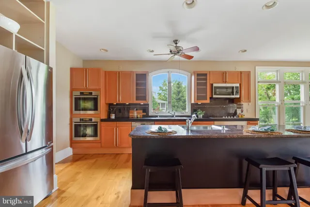 a kitchen with stainless steel appliances granite countertop a refrigerator a sink a stove a dining table and chairs