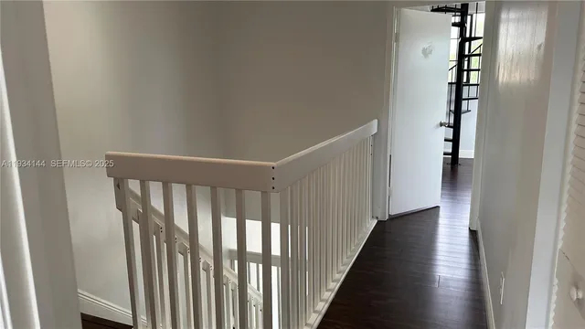 a view of a hallway with wooden floor and stairs
