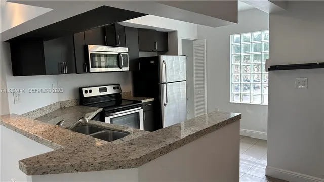 a kitchen with stainless steel appliances granite countertop a sink a stove and a refrigerator