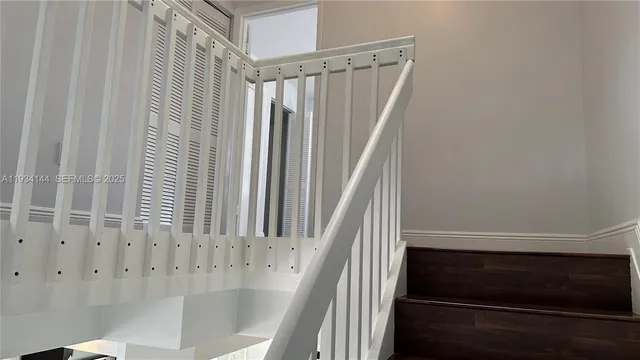 a view of staircase with railing and white walls