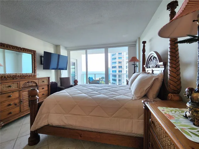 a bedroom with a bed and a flat tv screen on dresser