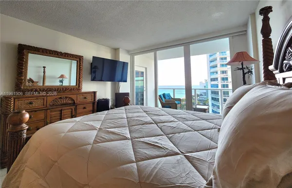 a bedroom with a bed and a flat tv screen on dresser
