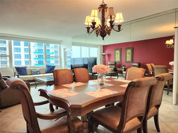 a view of a dining room with furniture a chandelier and large windows