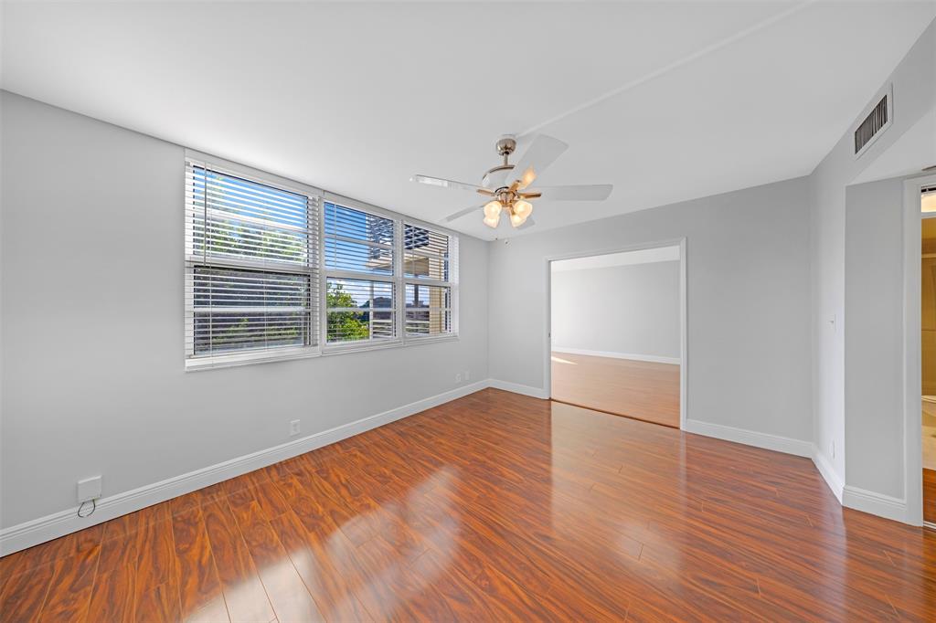 3520 Oaks Way, Unit 406 Pompano Beach, FL 33069 - Photo 21 of 32 a view of an empty room with wooden floor and a window