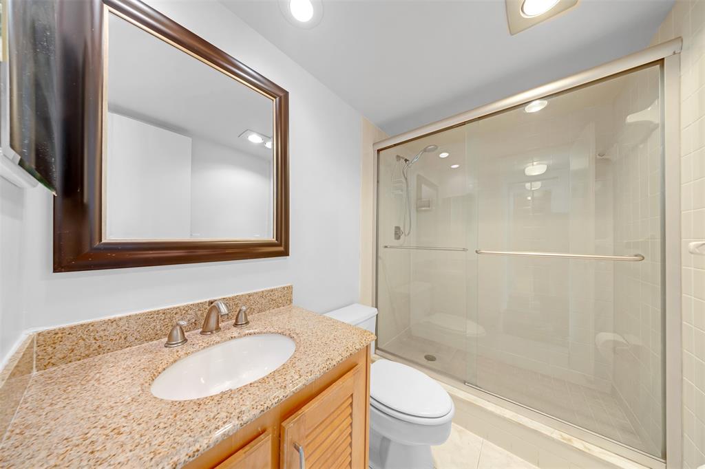 3520 Oaks Way, Unit 406 Pompano Beach, FL 33069 - Photo 22 of 32 a bathroom with a granite countertop sink toilet and shower