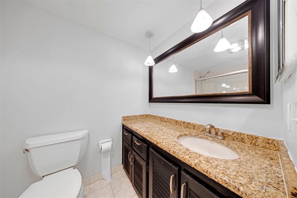 3520 Oaks Way, Unit 406 Pompano Beach, FL 33069 - Photo 27 of 32 a bathroom with a granite countertop toilet sink and mirror