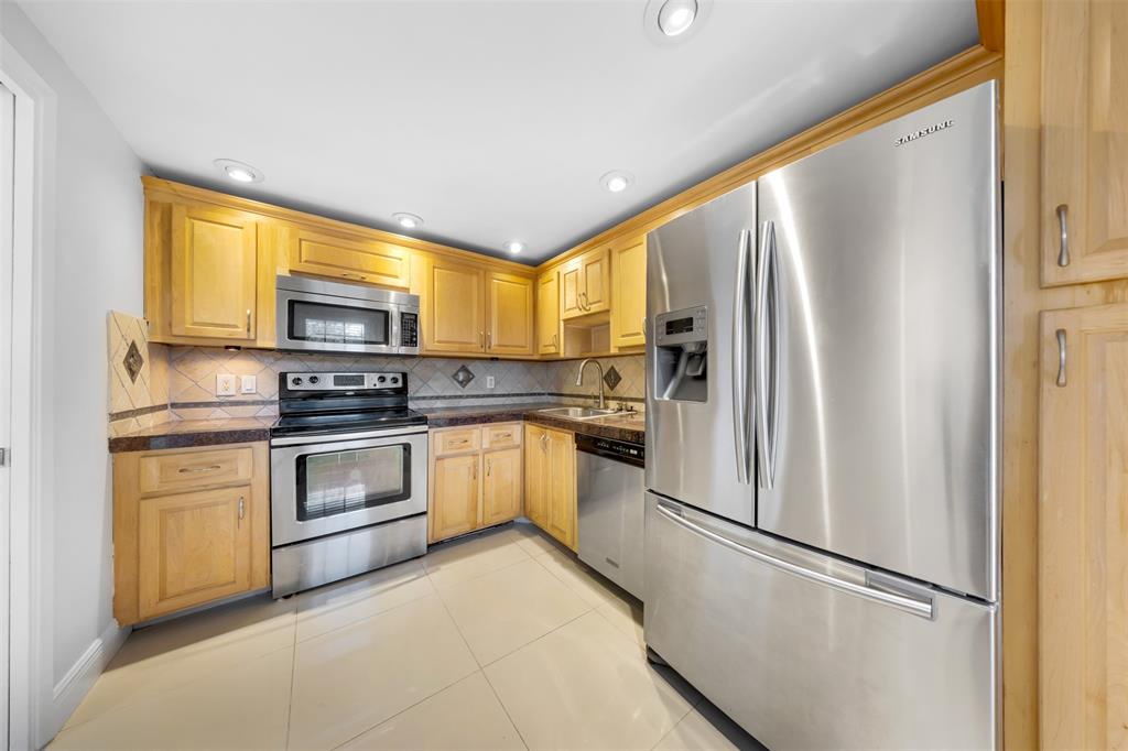 3520 Oaks Way, Unit 406 Pompano Beach, FL 33069 - Photo 3 of 32 a kitchen with stainless steel appliances a refrigerator sink and microwave