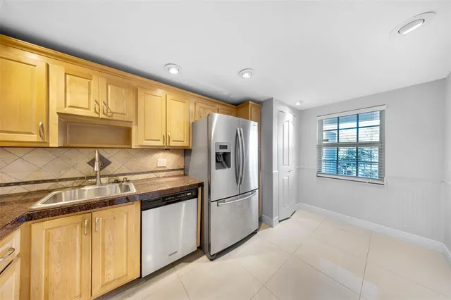 a kitchen with stainless steel appliances granite countertop a refrigerator a sink dishwasher a stove and white cabinets with wooden floor