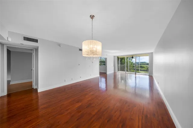 a view of a room with wooden floor ceiling fan and window