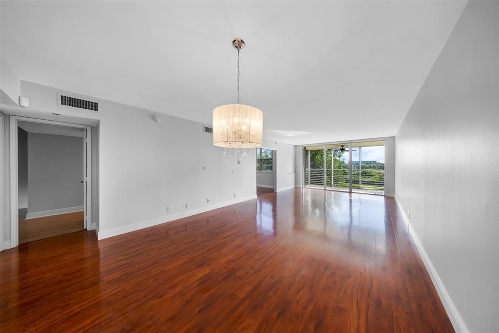 3520 Oaks Way, Unit 406 Pompano Beach, FL 33069 - Photo 7 of 32 a view of a room with wooden floor ceiling fan and window