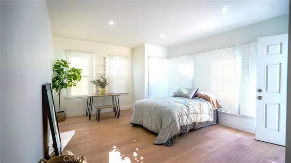 a bedroom with a bed table chair and a potted plant