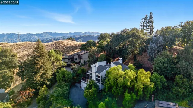 a front view of a house with a yard and mountain view in back