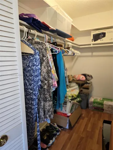 a view of walk in closet with clothes and shoes