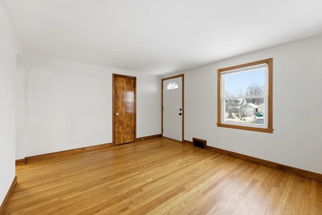 a view of an empty room with window and wooden floor