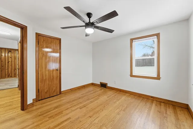 an empty room with wooden floor a ceiling fan and windows