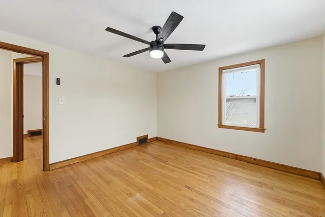 a view of empty room with wooden floor and fan