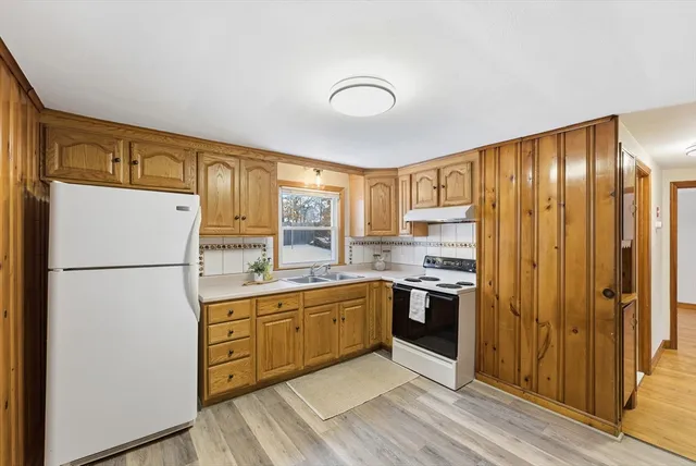 a kitchen with stainless steel appliances granite countertop a refrigerator a sink a stove and white cabinets with wooden floor