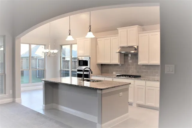 a kitchen with stainless steel appliances granite countertop a sink a stove and a refrigerator