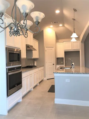 a kitchen with kitchen island granite countertop a sink a stove and microwave
