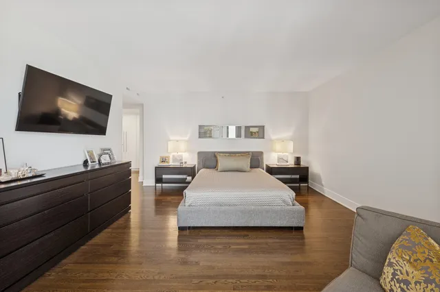 a spacious bedroom with a bed and a flat screen tv