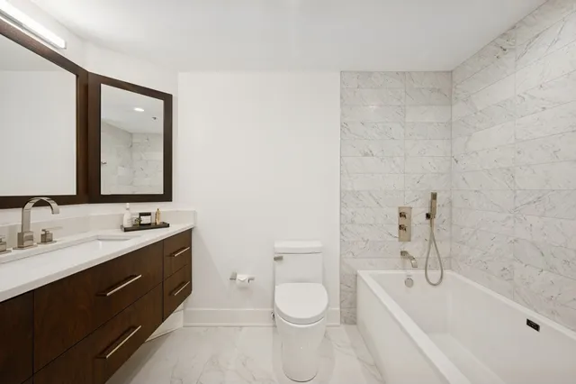 a bathroom with a double vanity sink toilet mirror and bathtub