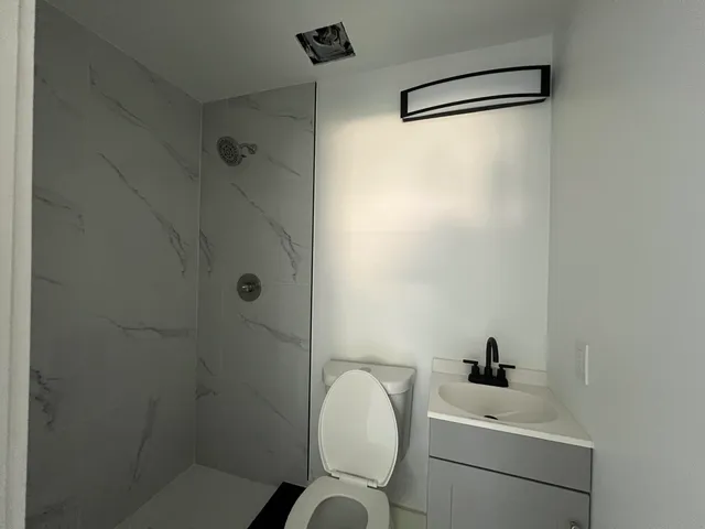 a bathroom with a toilet sink vanity and shower