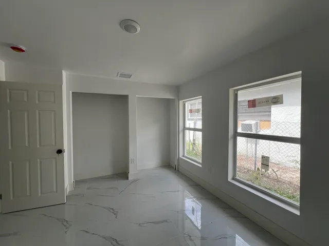 a view of an empty room with window and bathroom
